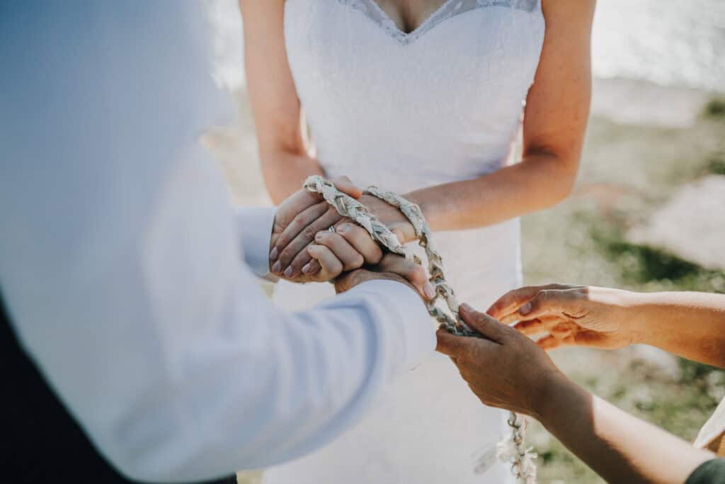 Brautpaar bei Handzeremonie mit geflochtener Schnur. Hände, Kleid. Hochzeitsfotograf Irland.