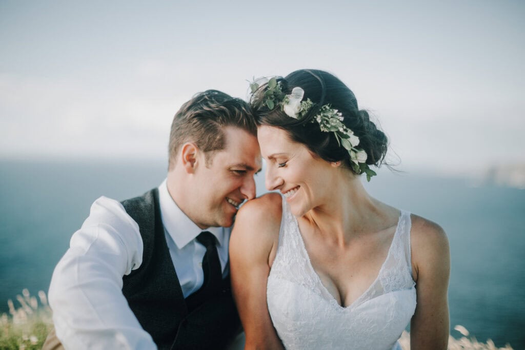 Brautpaar lächelt sich an, Blumenschmuck im Haar, Irland Hochzeit.