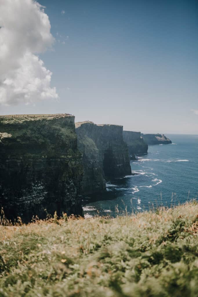 Spektakuläre Cliffs of Moher in Irland mit Blick auf den Atlantik unter blauem Himmel.