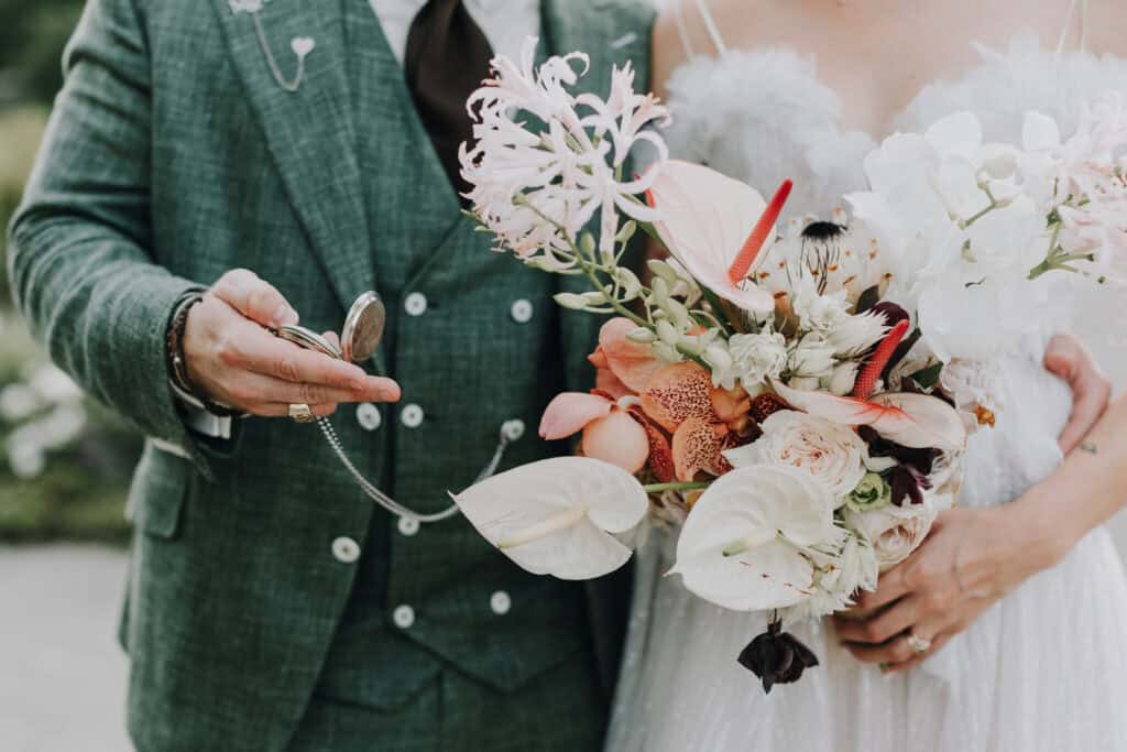 Bräutigam mit Taschenuhr, Braut mit Blumenstrauß. Hochzeit in München?