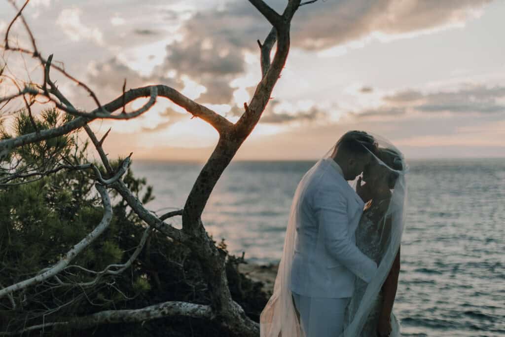 Brautpaar unter Schleier vor Ibiza-Sonnenuntergang. Romantische Hochzeit auf Ibiza.