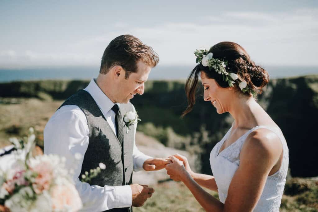 Brautpaar tauscht Ringe bei einer irischen Hochzeit im Freien mit Meerblick.