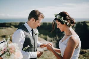 Brautpaar tauscht Ringe bei einer irischen Hochzeit im Freien mit Meerblick.