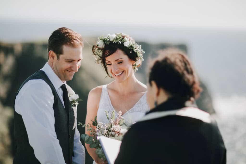 Brautpaar bei irischer Hochzeitszeremonie mit Blumenkranz und Blick auf die Klippen.