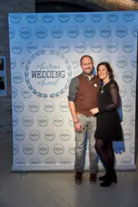 Mann und Frau posieren vor "Austrian Wedding Award" Hintergrund. Festliche Kleidung, lächelnd.