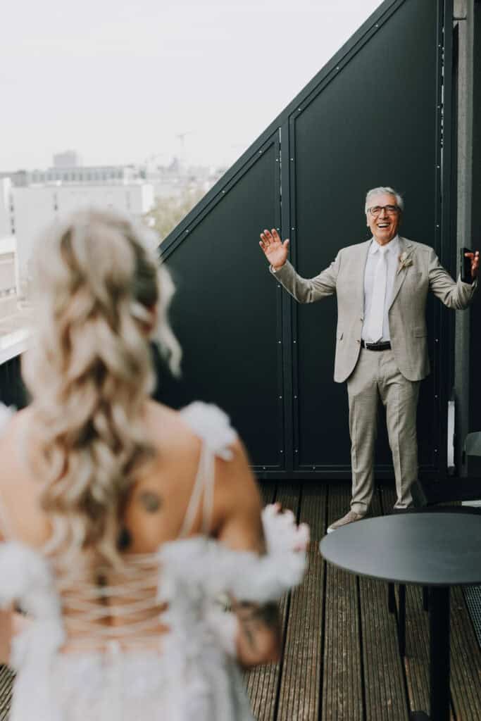 Braut und stolzer Vater am Hochzeitstag auf Balkon. Glücklicher Moment in München.