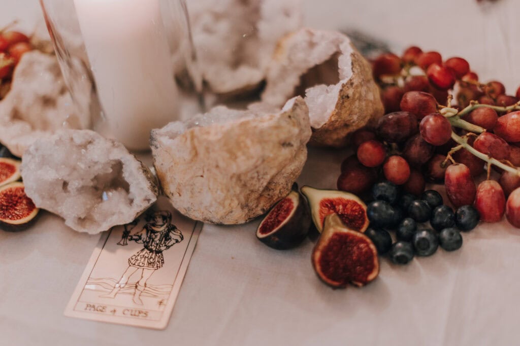 Hochzeitsdeko mit Geoden, Früchten, Tarotkarte Page of Cups. Ibiza Hochzeitsfotograf Inspiration.