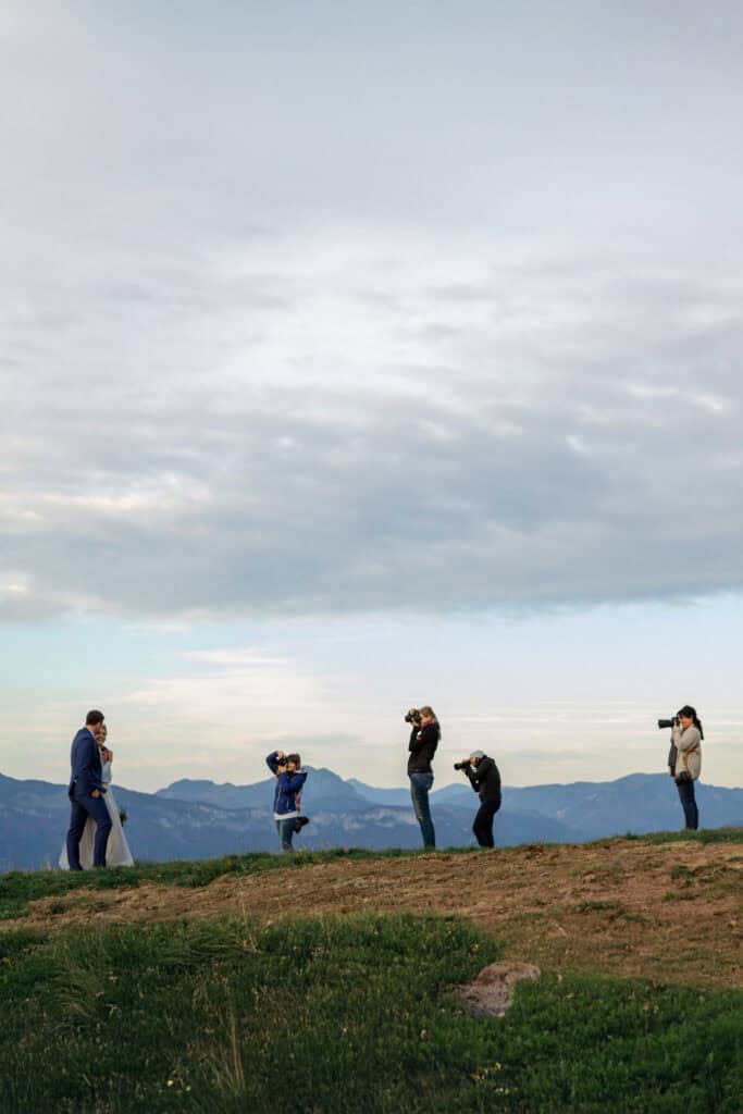 Hochzeitsfotografen Workshop: Brautpaar wird vor Bergkulisse fotografiert. Kameras im Einsatz.