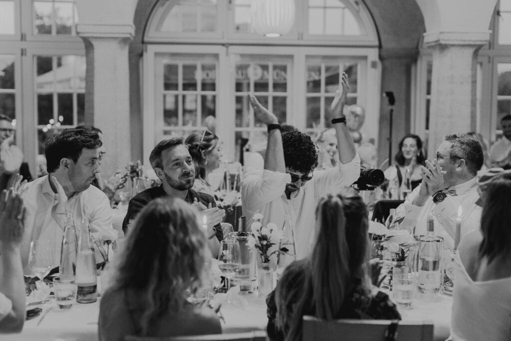 Hochzeitsgäste applaudieren bei einer Hochzeitsfeier in München. Festliche Stimmung, elegante Dekoration.