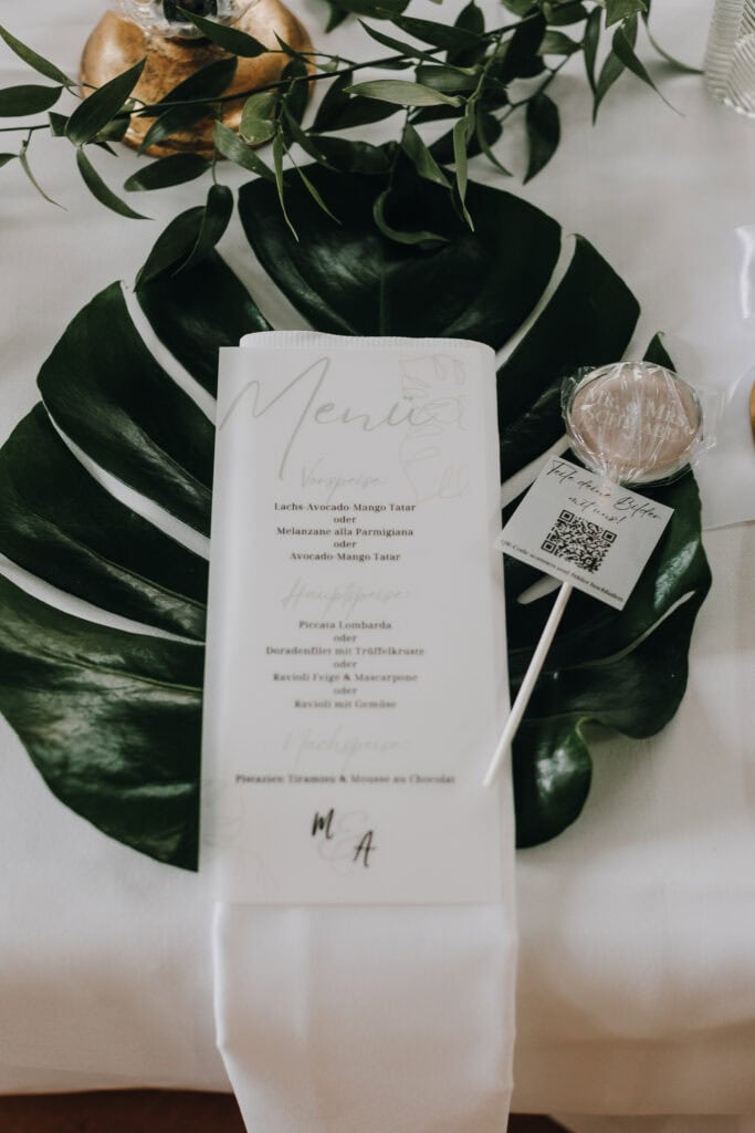 Hochzeitsmenü mit Monstera Blatt und QR-Code für Fotos teilen. Menükarte mit Speisenfolge.