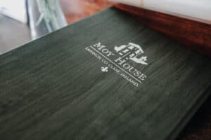 Moy House Menü in Lahinch, Irland. Logo des Hotels auf dunklem Holz. Hochzeit in Irland.
