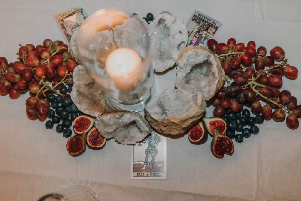 Tischdeko mit Kerze, Geoden, Trauben, Feigen und Tarotkarten. Romantische Tischdekoration.