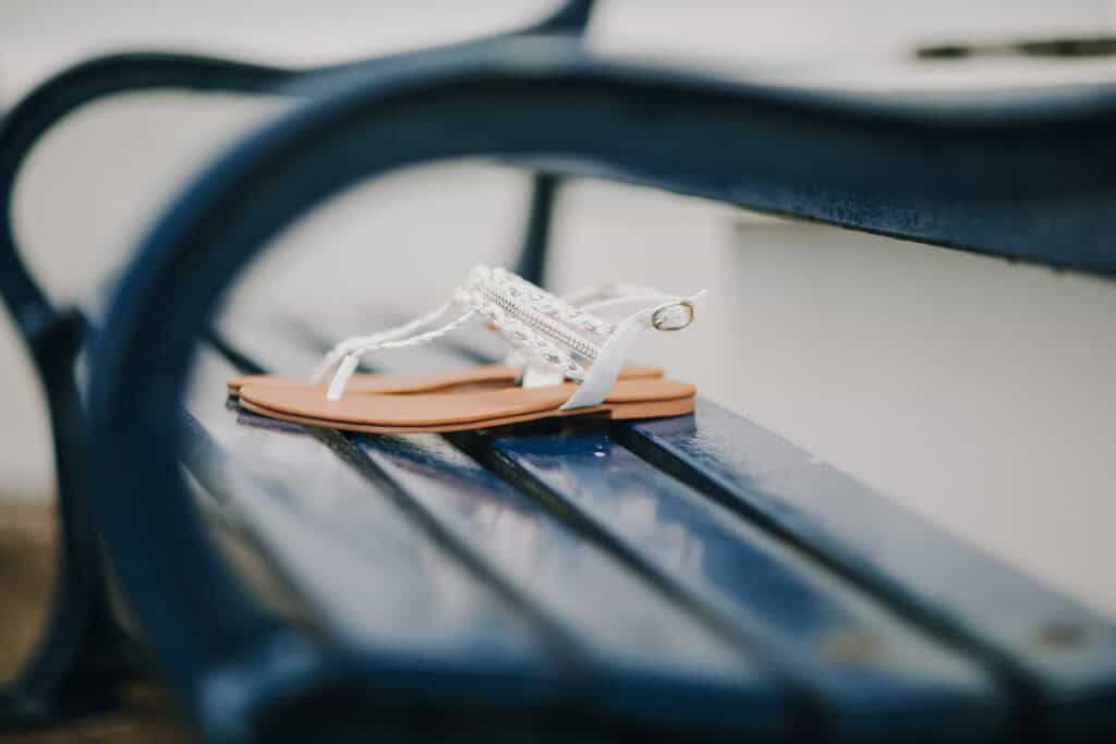 Weiße Sandalen auf blauer Bank. Sommerliche Schuhe, lässig und elegant.