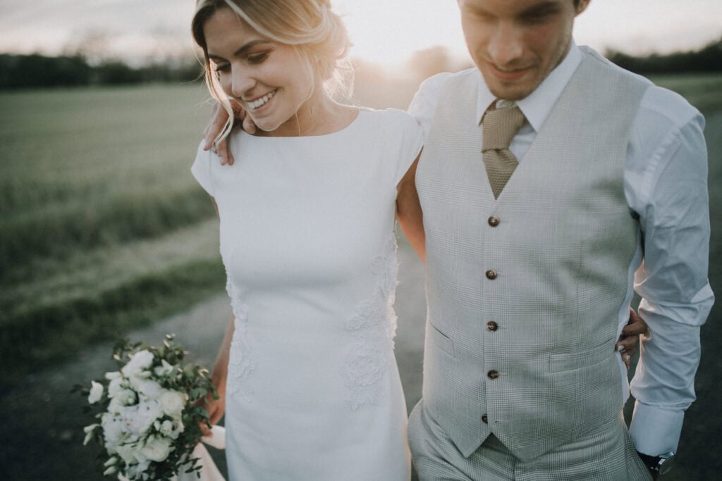 Brautpaar im Gegenlicht, die Braut hält einen Blumenstrauß. Hochzeitsfotograf Tirol.