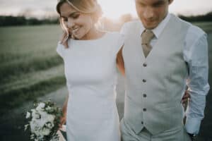 Brautpaar im Gegenlicht, die Braut hält einen Blumenstrauß. Hochzeitsfotograf Tirol.
