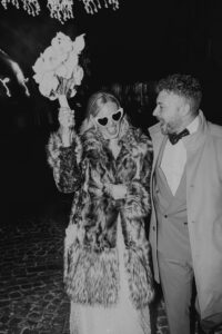 Brautpaar feiert mit Herzbrille und Blumenstrauß. Hochzeitsfotograf Tirol.