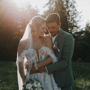 Brautpaar umarmt sich im goldenen Licht. Braut mit Blumenstrauß. Hochzeitsfotograf Tirol.