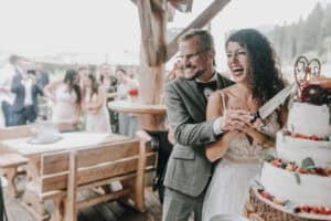 Brautpaar schneidet Hochzeitstorte an. Glückliche Hochzeit in Tirol.