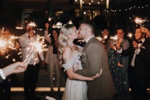 Brautpaar küsst sich bei Hochzeit mit Wunderkerzen. Hochzeitsfotograf Tirol. Romantisch, festlich.