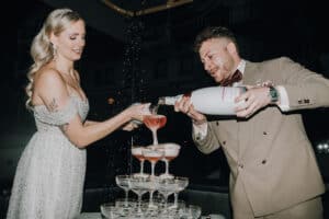 Brautpaar gießt Champagner in Gläserpyramide. Hochzeit in Tirol.