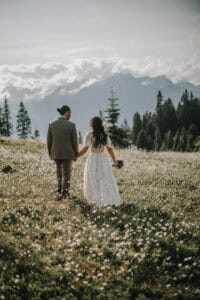 Brautpaar hält Händchen in den Tiroler Alpen. Hochzeit im Freien mit Blick auf die Berge.