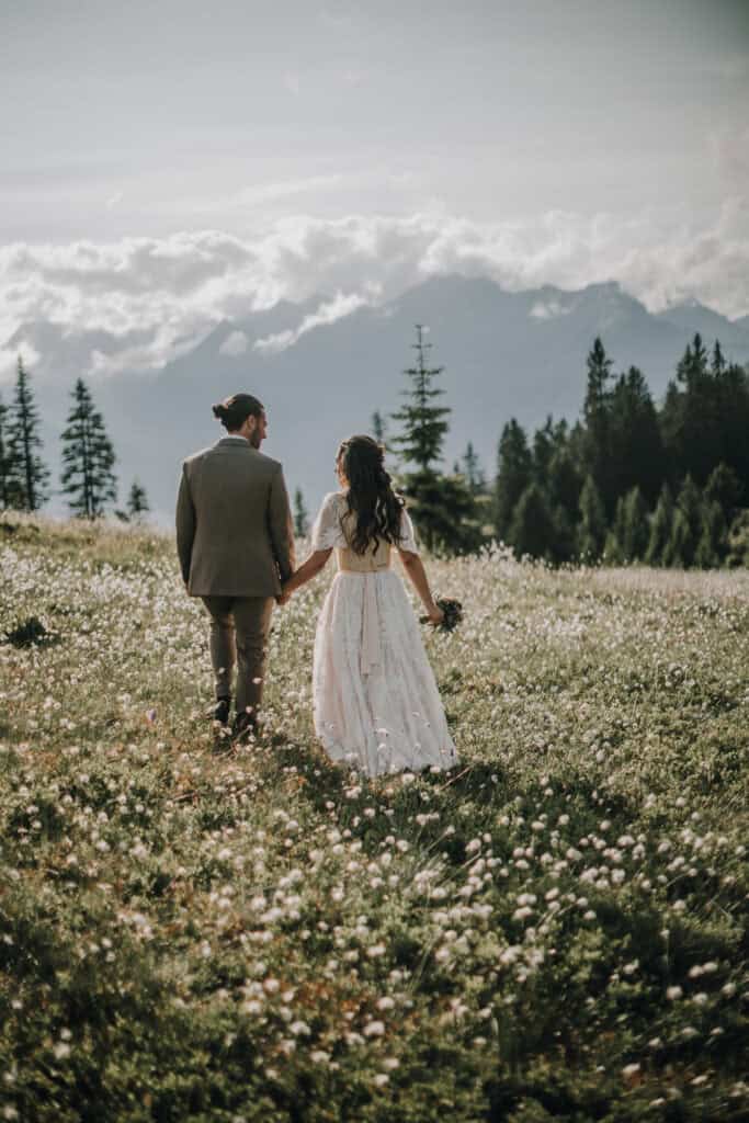 Brautpaar hält Händchen in den Tiroler Alpen. Hochzeit im Freien mit Blick auf die Berge.