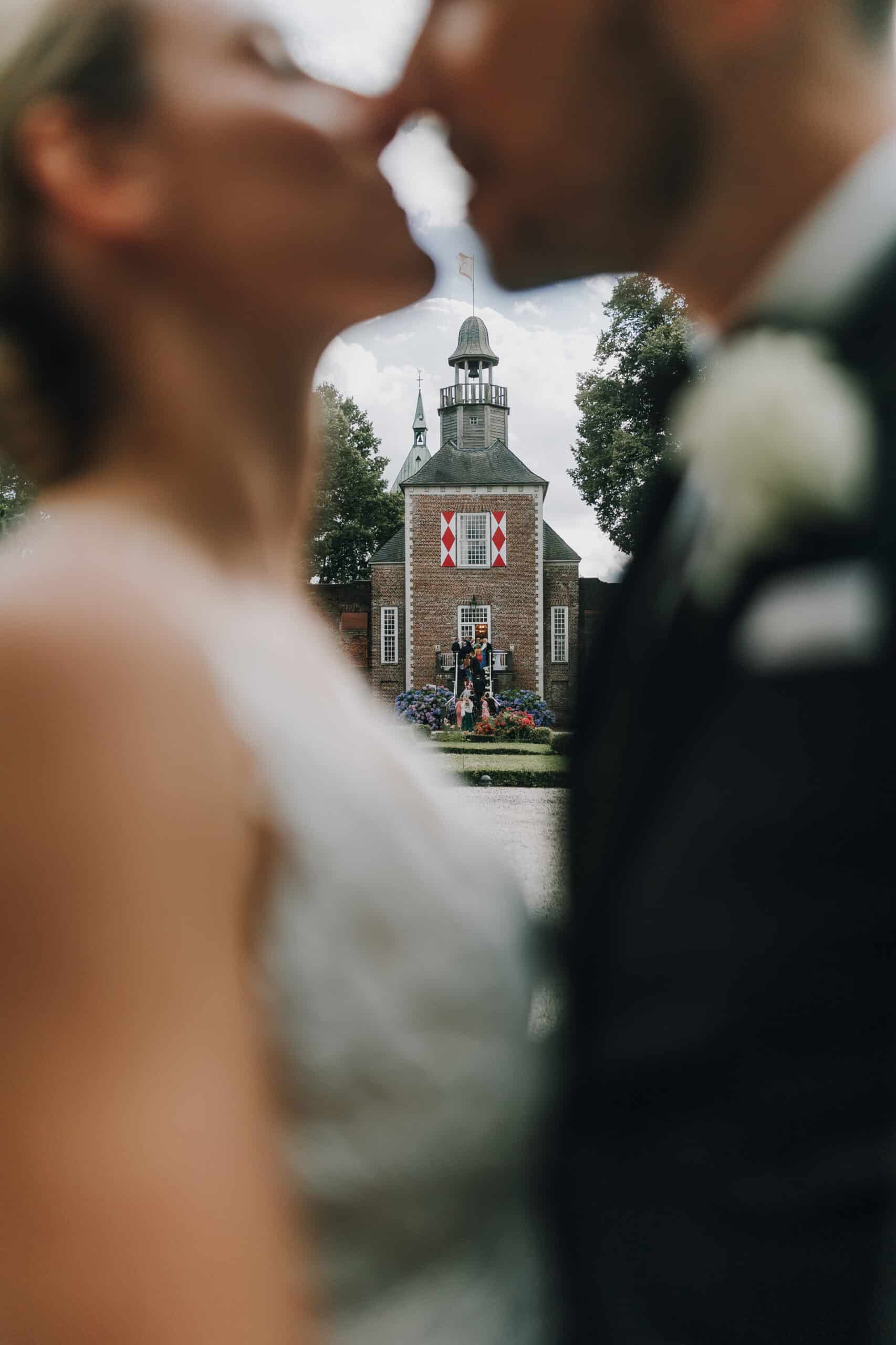 Brautpaar küsst sich vor Schloss. Hochzeitsfotograf Tirol könnte dieses Schloss für Paarfotos nutzen.