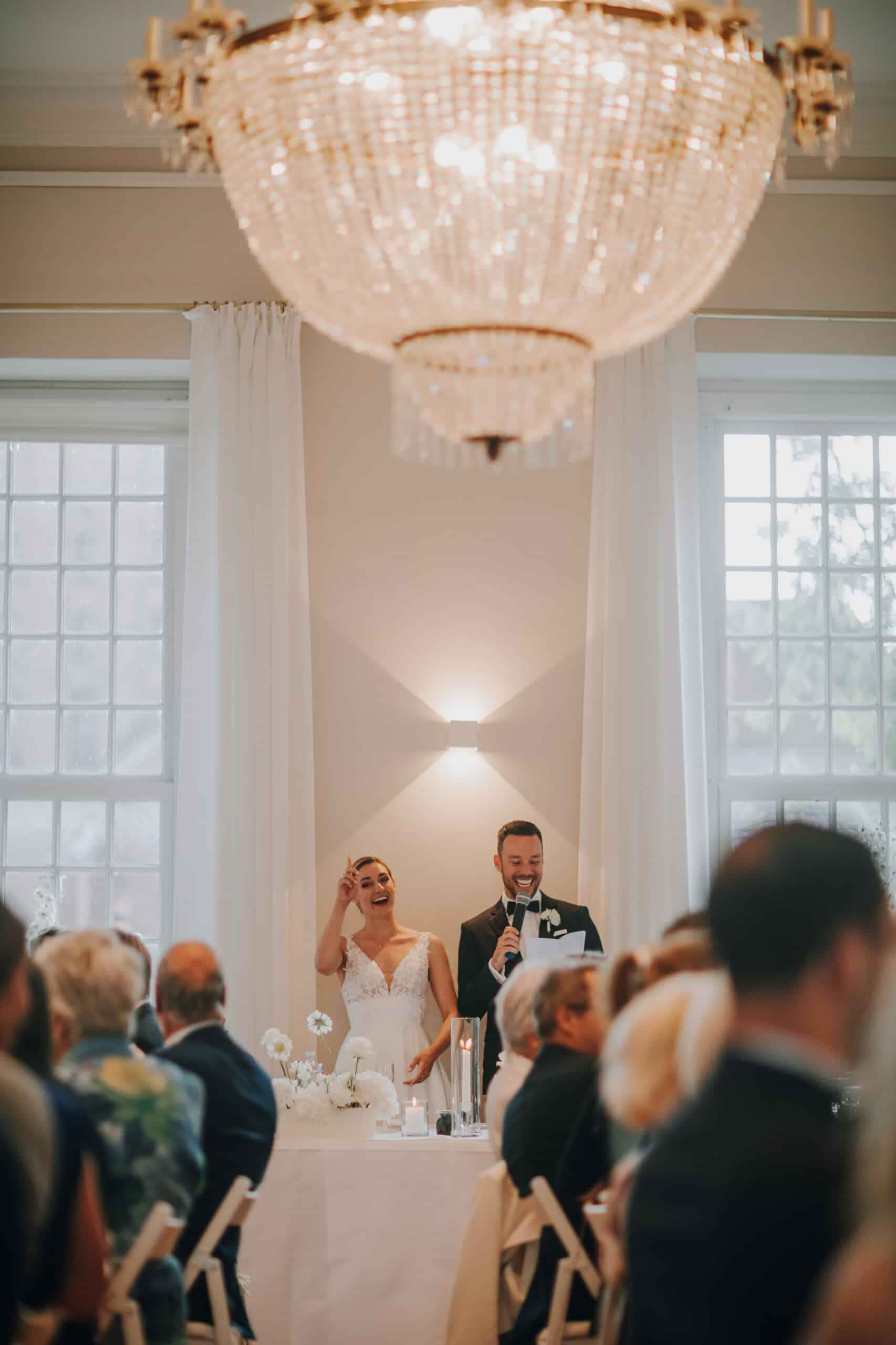 Brautpaar hält Rede unter Kronleuchter. Hochzeitsfotograf Tirol.