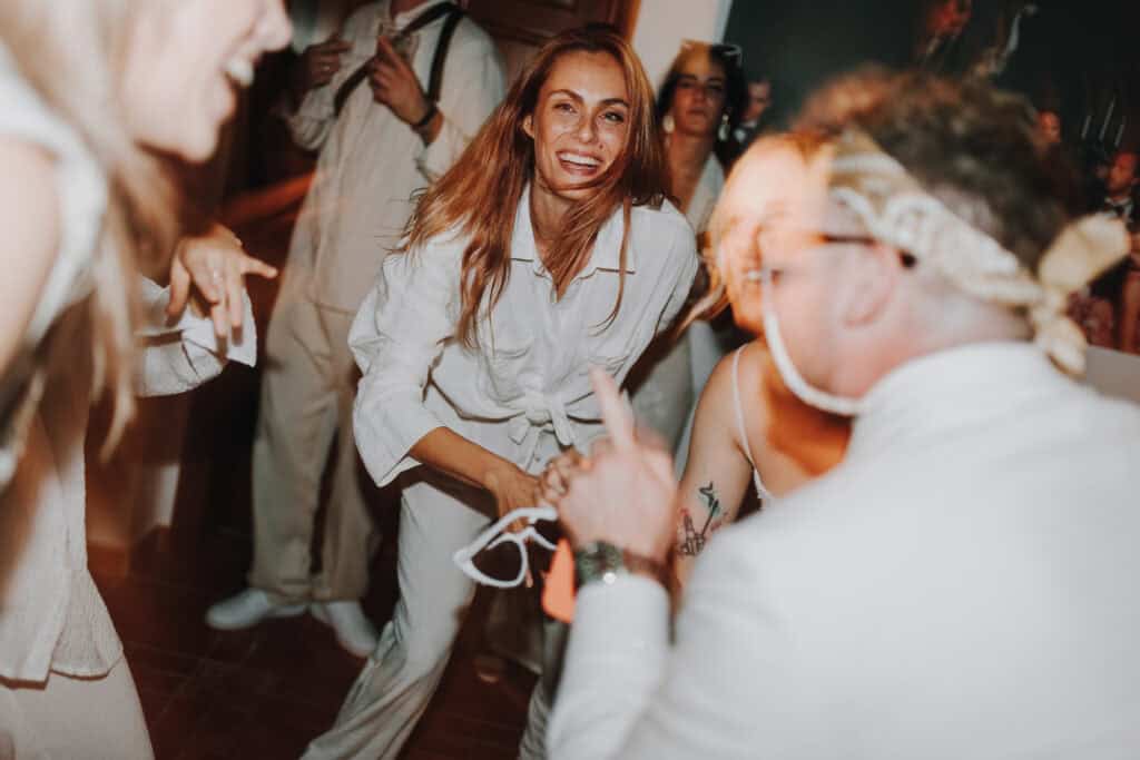 Fröhliche Frau tanzt auf Hochzeit. Brautpaar feiert ausgelassen in Tirol.
