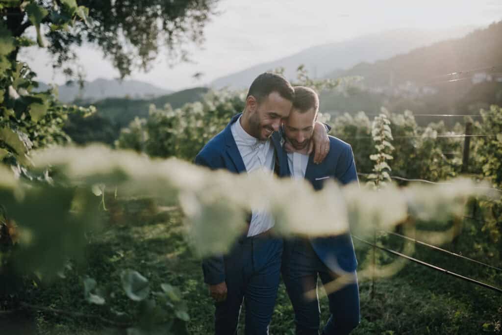 Zwei Männer in Anzügen umarmen sich in einem Weinberg. Hochzeitsfotograf Tirol.